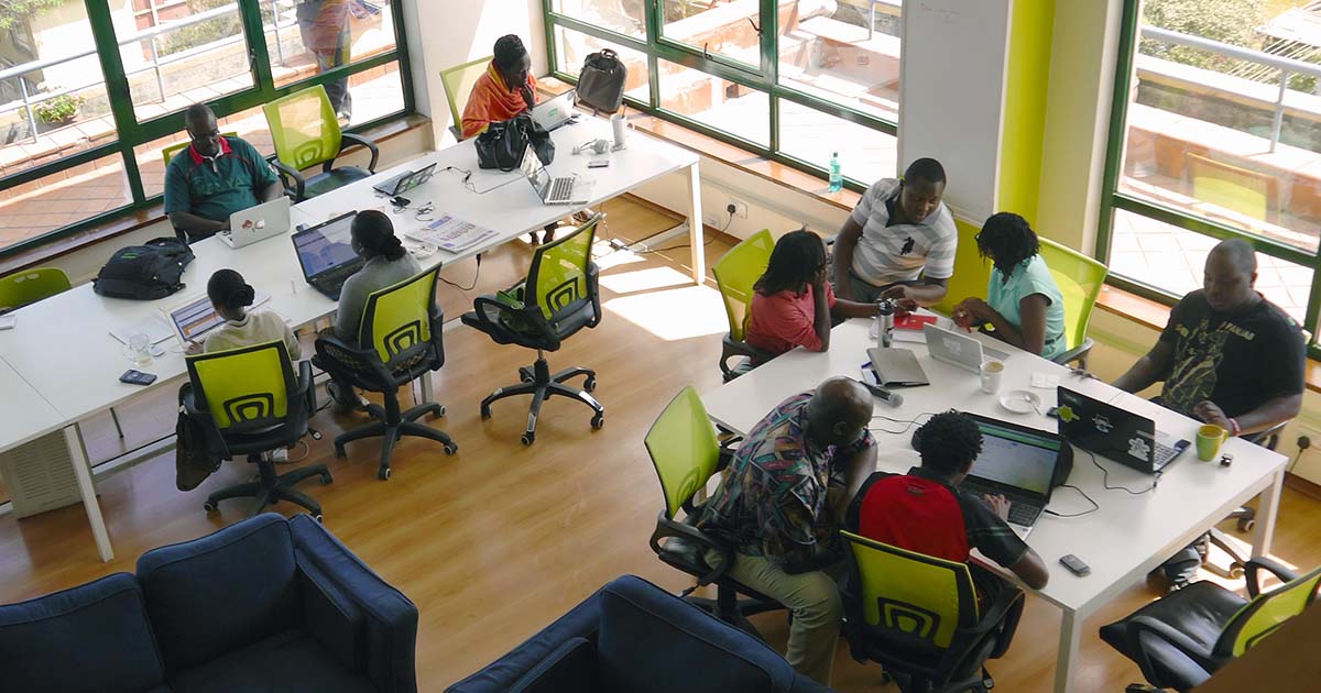 Office environment with people some working on their laptops and others in a discussion